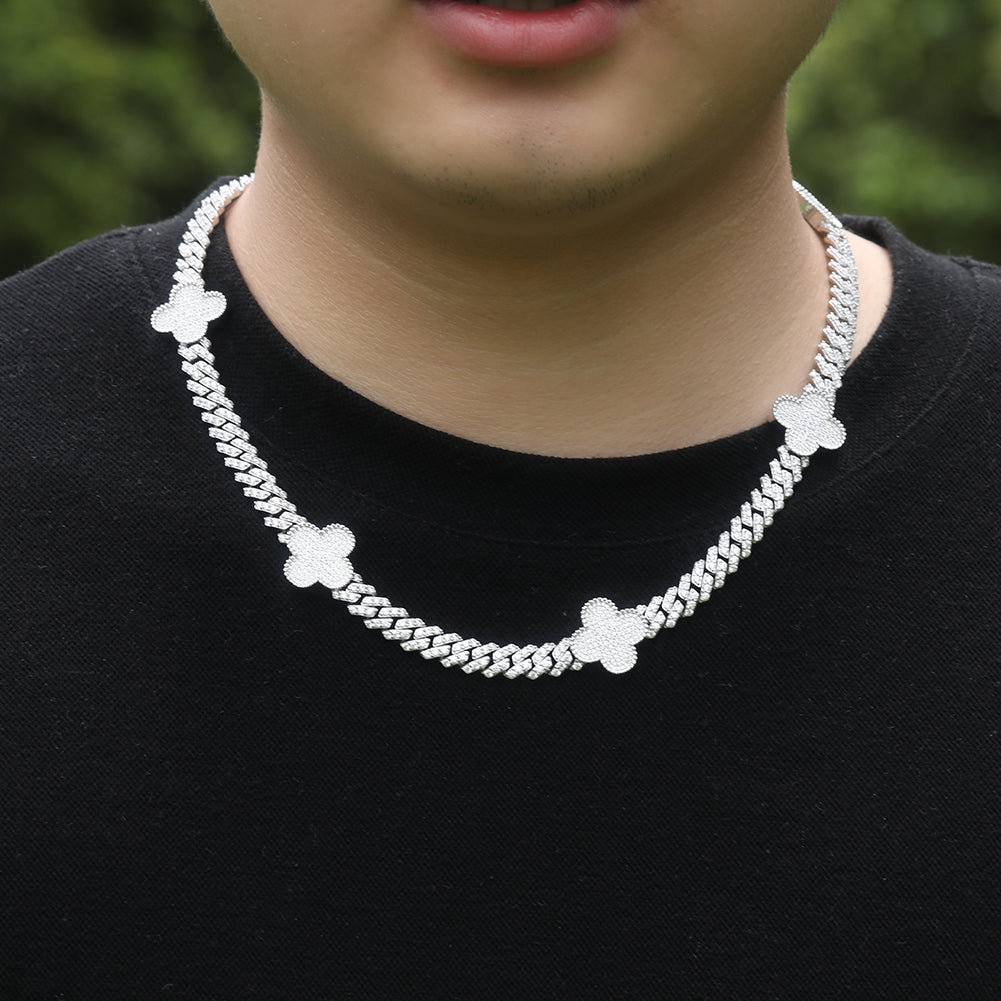 Silver chain necklace with floral designs worn by a person against a blurred green background